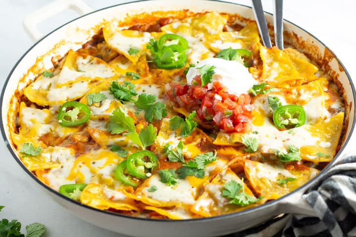Close up shot of a large skillet filled with vegetarian enchiladas garnished with fresh cilantro