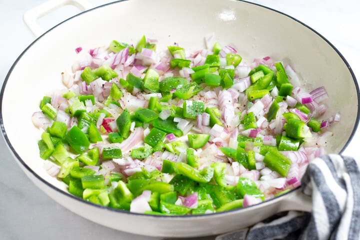 White saute pan filled with onion and green pepper