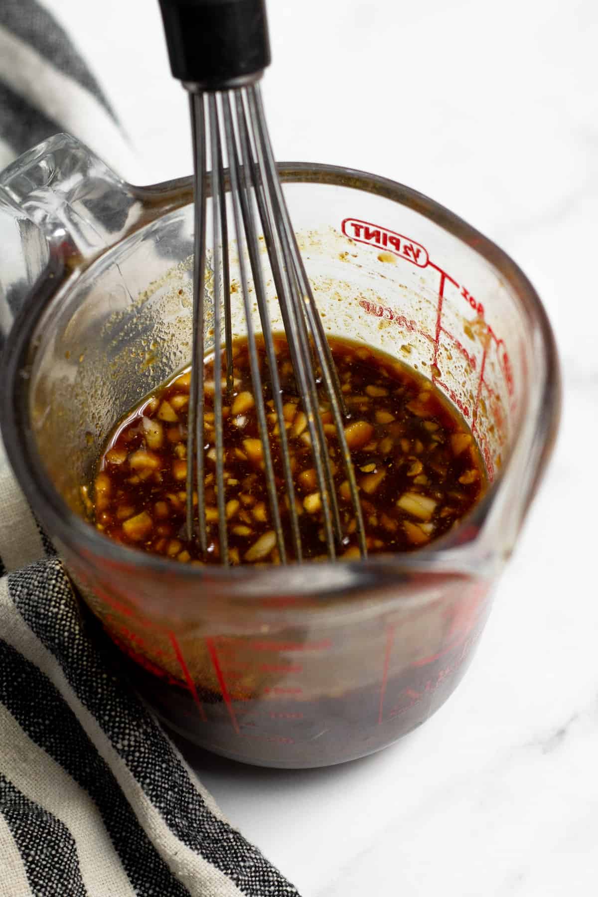 Close up shot of a measuring cup filled with Korean inspired sauce for Korean beef tacos