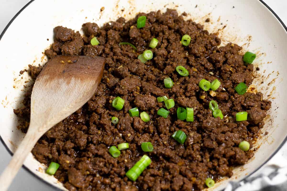 Korean flavored ground beef in a large saute pan garnished with sliced green onion