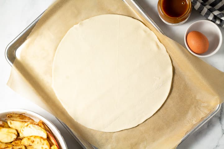A parchment lined baking sheet with a pie crust on it