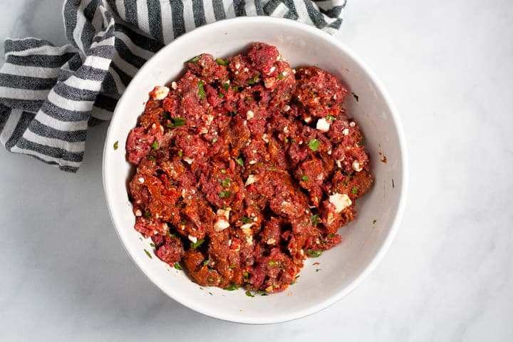 Large white bowl filled with ingredients to make Mexican burgers