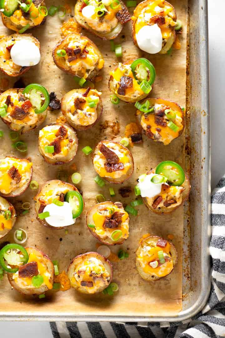 Overhead shot of jalapeno popper potato skins on a parchment lined baking sheet