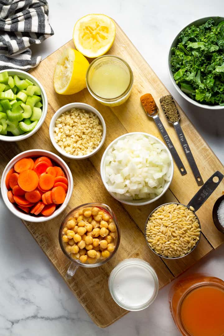 Wooden cutting board filled with ingredients to make creamy vegan lemon orzo soup