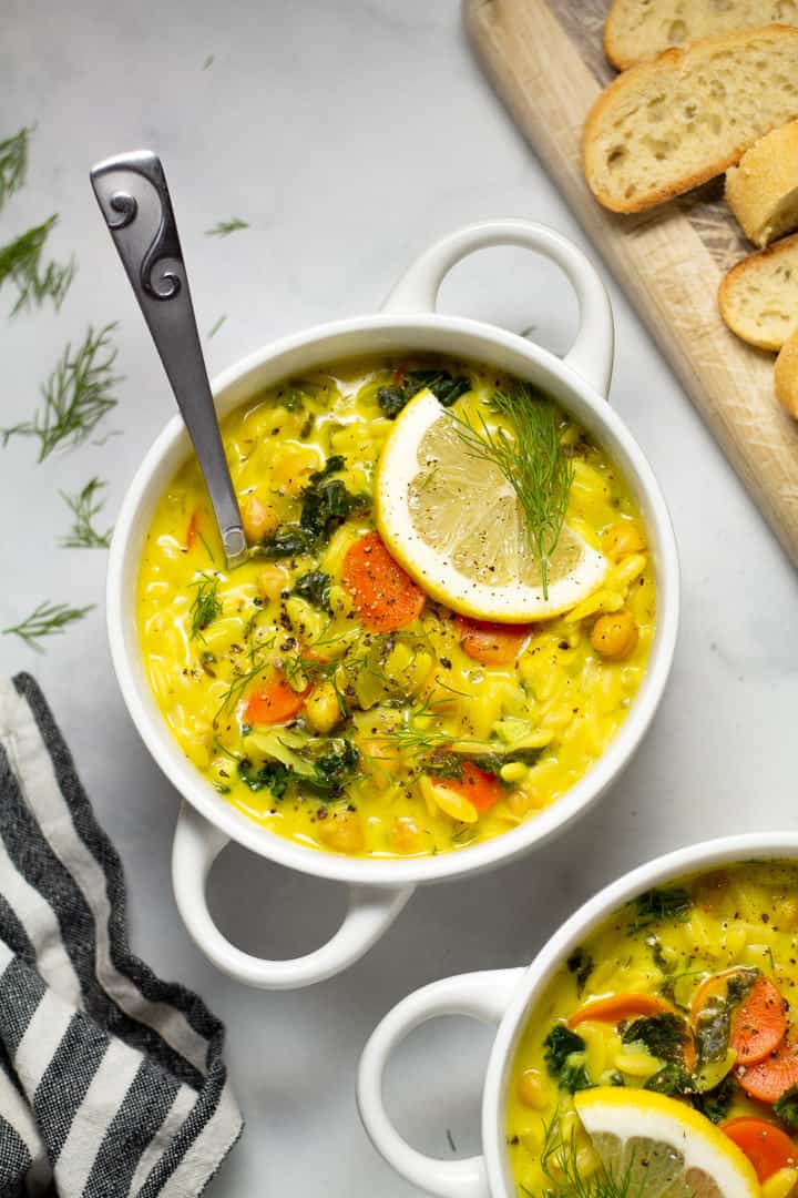 Overhead shot of lemon orzo soup in a white bowl garnished with fresh dill