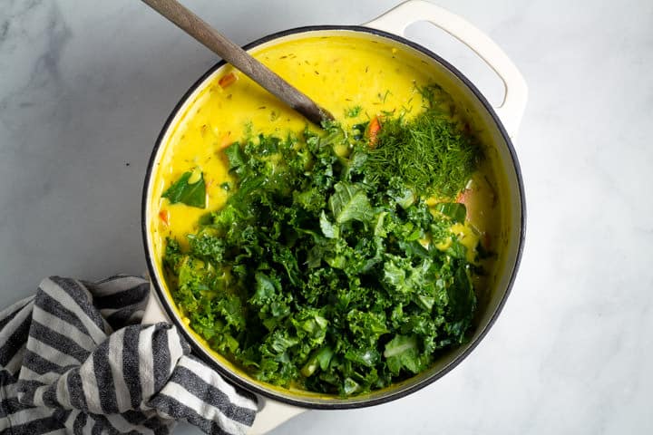 Large white dutch oven filled with creamy vegan lemon orzo soup
