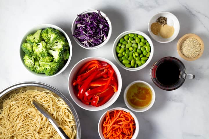 White marble counter top covered with the ingredients to make veggie lo mein