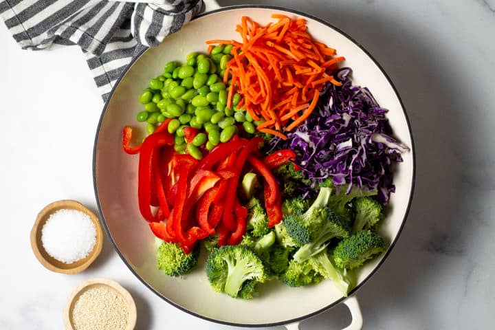 Overhead shot of the ingredient to make veggie lo mein in a large white saute pan