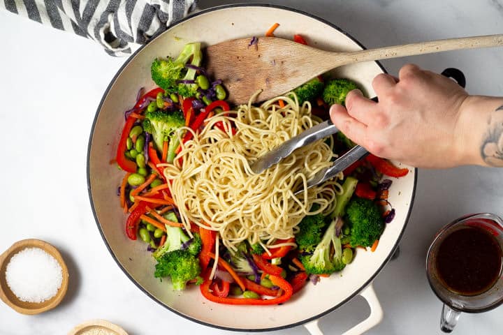 Overhead shot of noodles being added to a pan of veggie lo mein