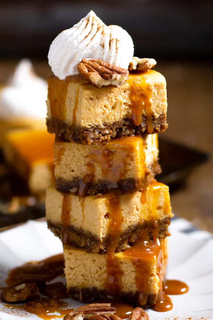 Tower of pumpkin cheesecake bars garnished with caramel and pecans