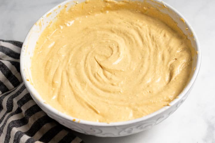 Large white bowl filled with ingredients to make pumpkin cheesecake filling