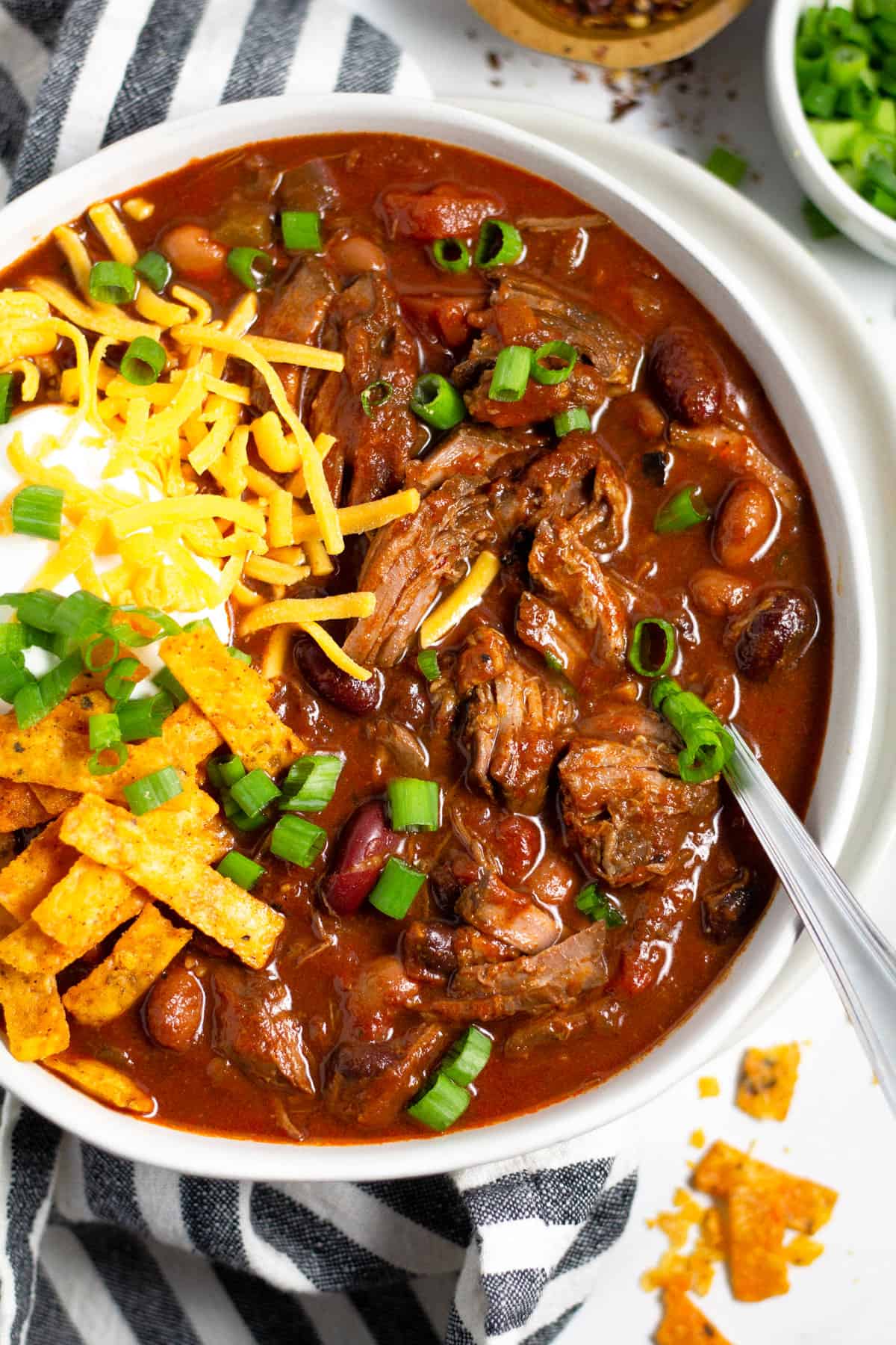Overhead shot of a bowl of short rib beef chili topped with sour cream and cheese