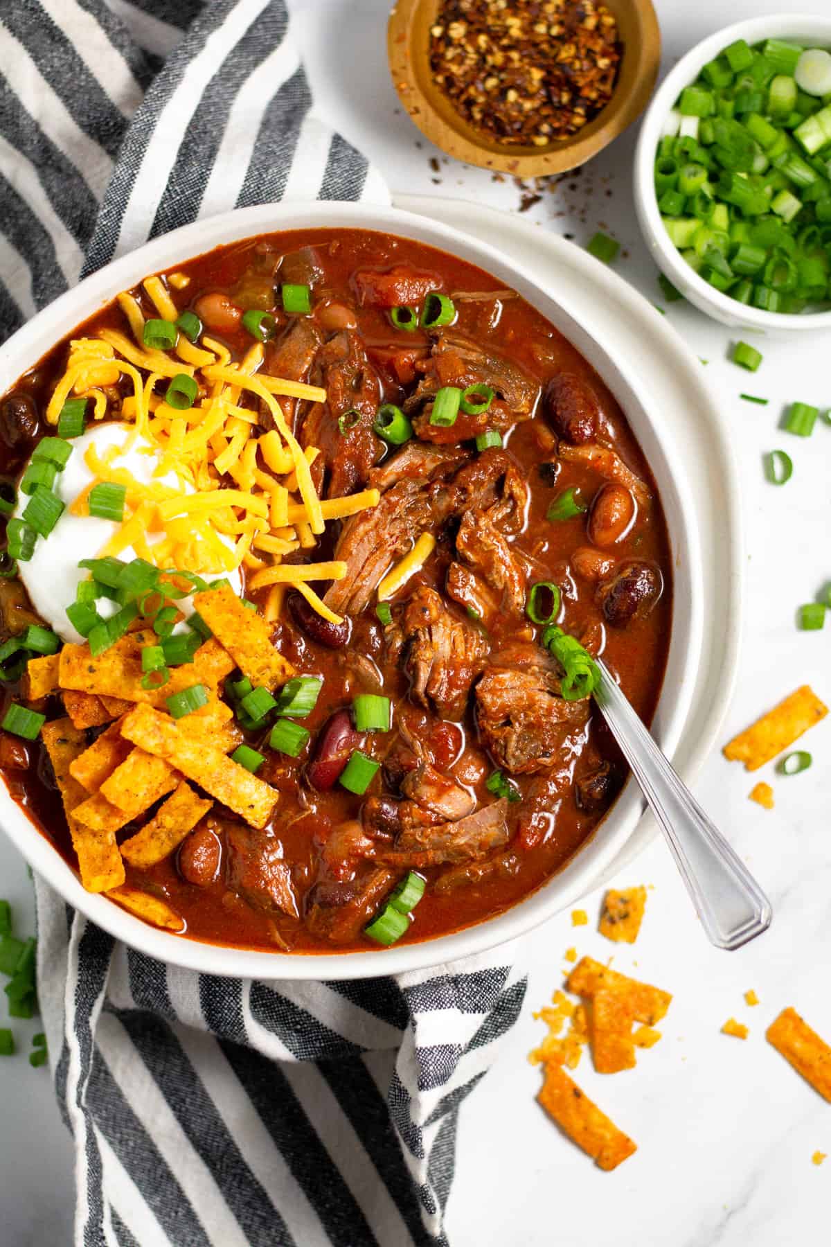 Overhead shot of a bowl of short rib beef chili topped with sour cream and cheese