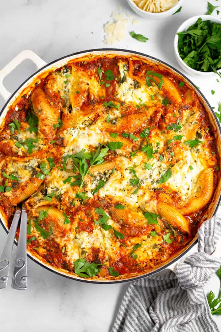 Overhead shot of a large white pan filled with stuffed shells garnished with fresh parsley