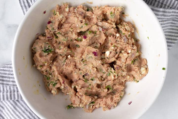 Large white bowl filled with ingredients to make Greek turkey burgers