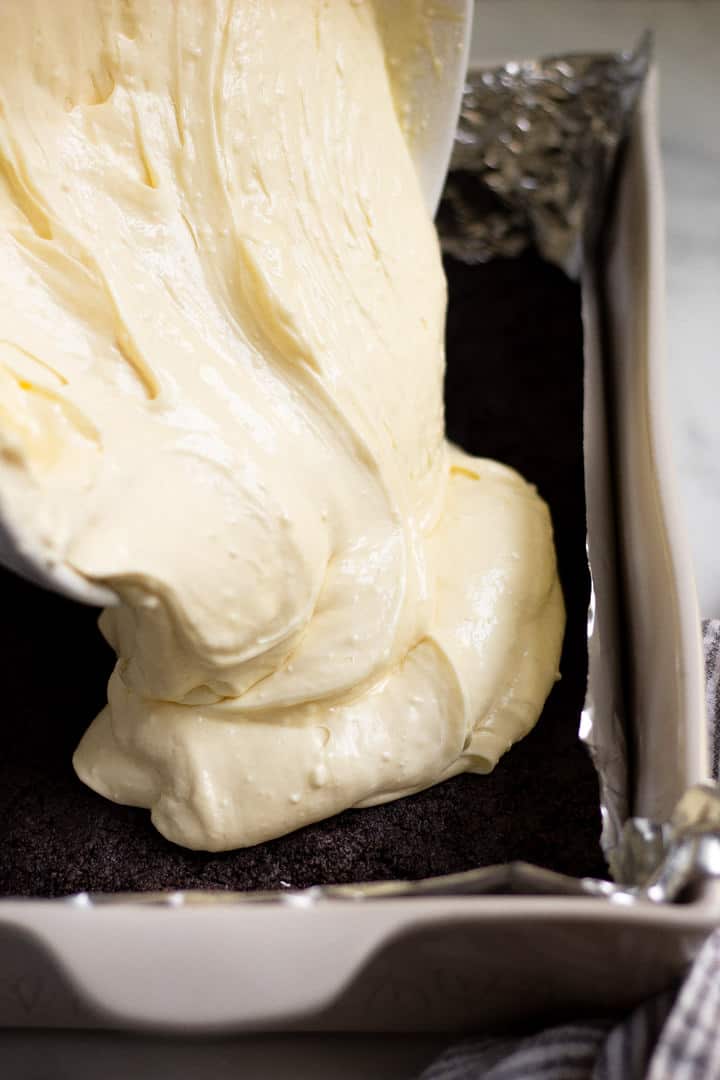 Cheesecake batter being poured onto an oreo crust