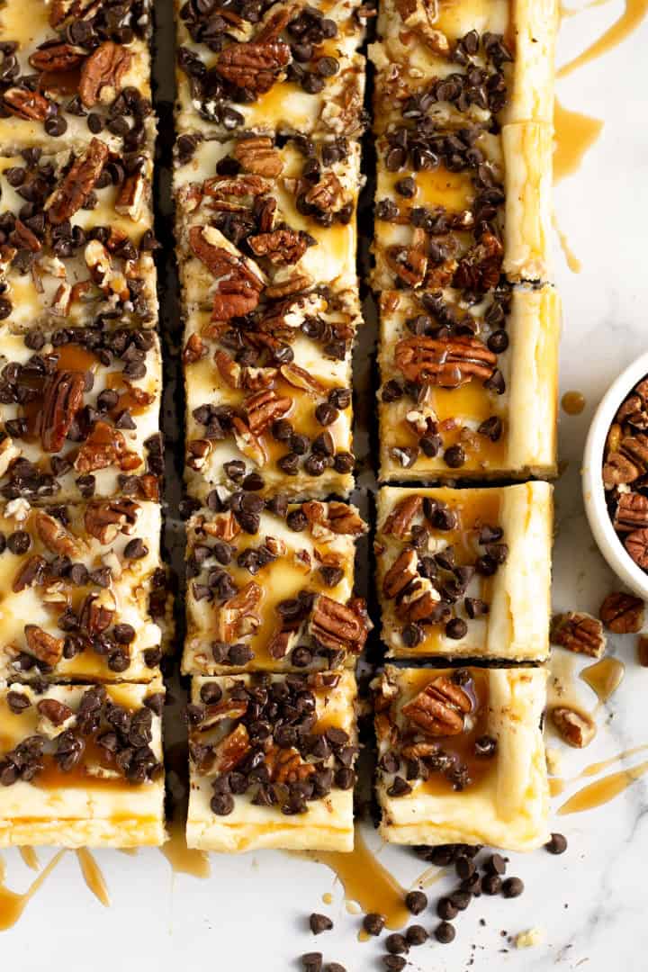 Close up shot of turtle cheesecake bars topped with chocolate and caramel