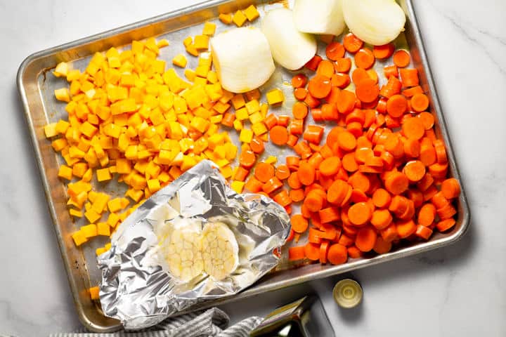 Baking sheet filled with carrots squash onion and garlic