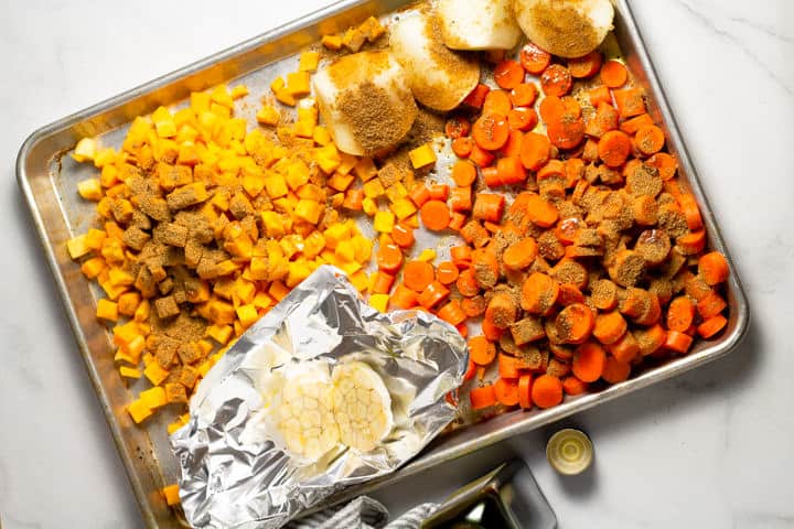Baking sheet filled with veggies seasoned with spices