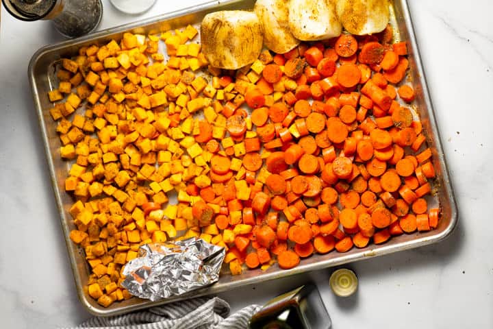 Baking sheet filled with veggies seasoned with spices
