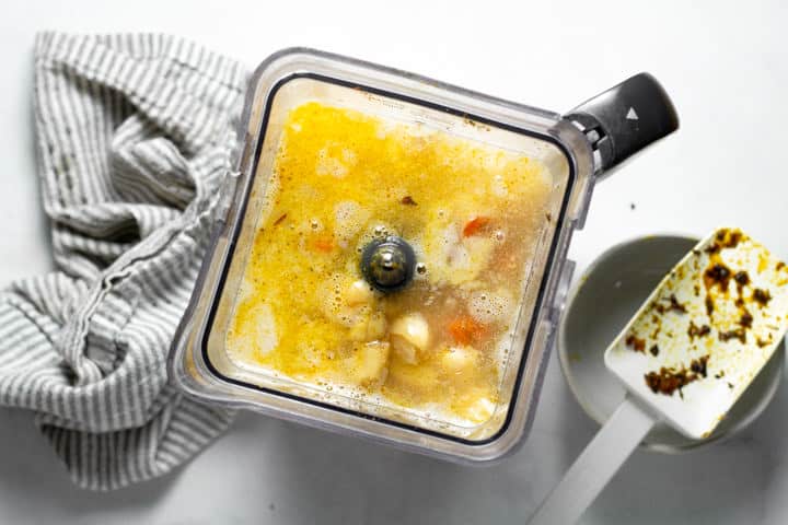 Overhead shot of a blender filled with roasted veggies and broth