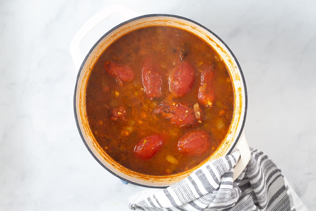 Large white pot filled with ingredients to make vegan tomato soup
