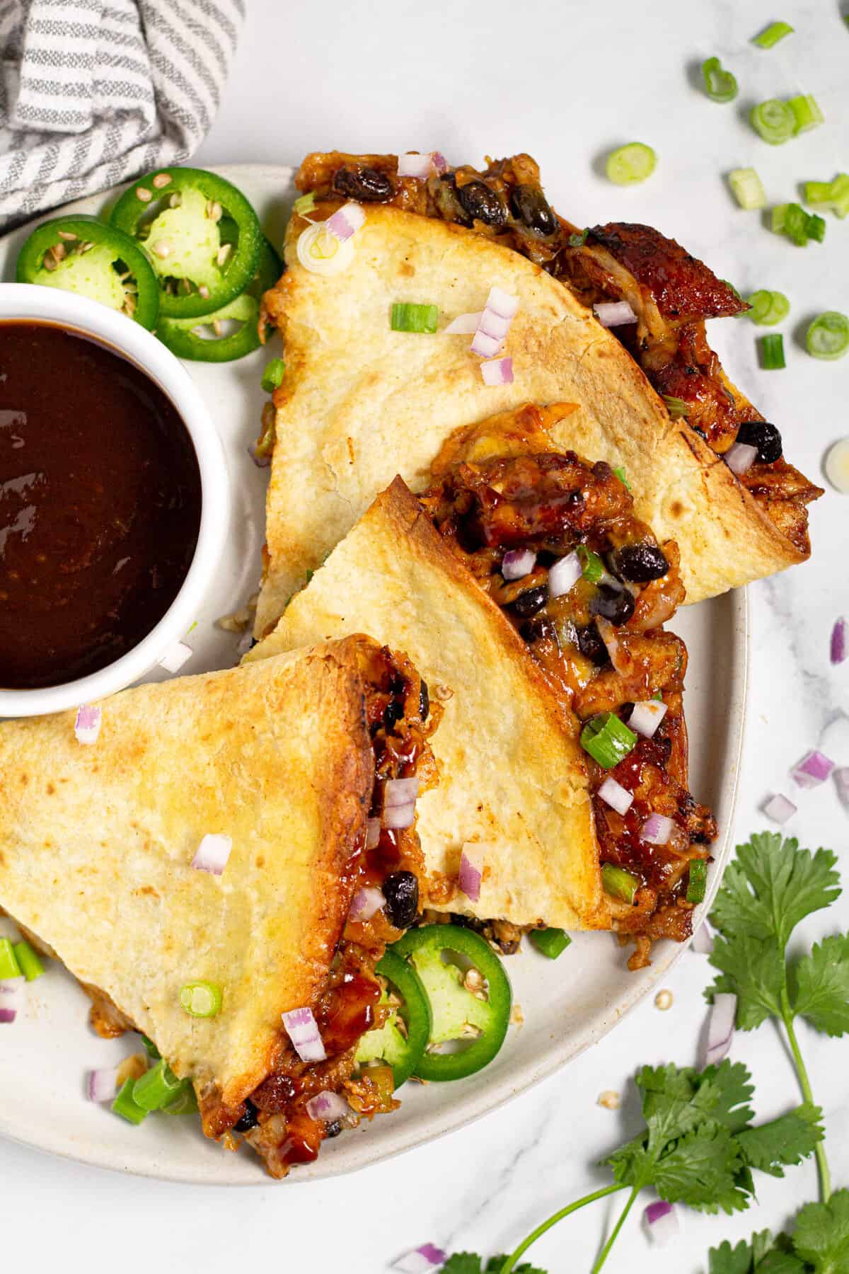 Overhead shot of a plate of barbecue chicken quesadillas garnished with green onion