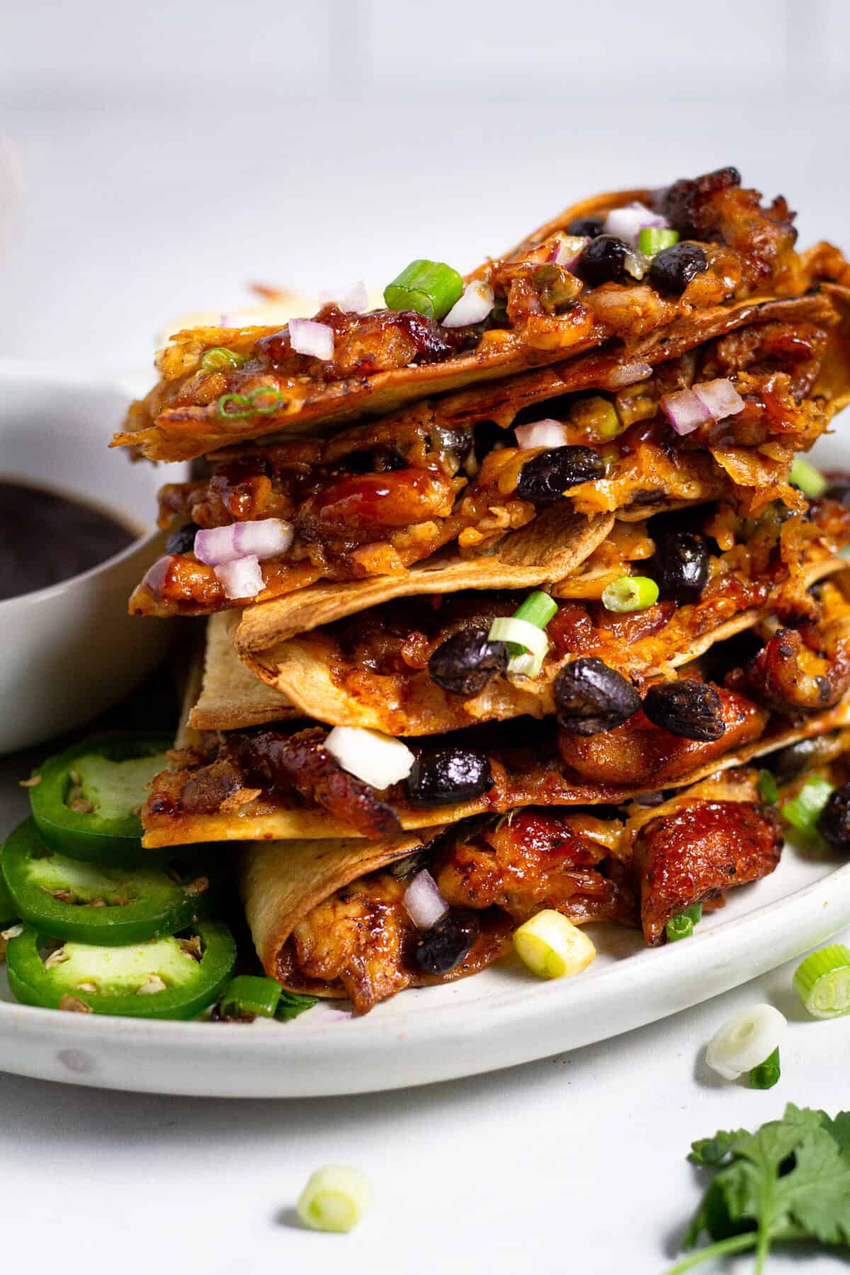 Barbecue chicken quesadillas sliced and stacked on a large white plate