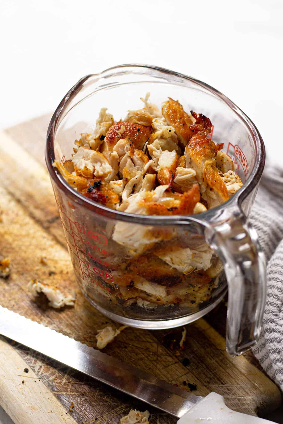 A glass measuring cup filled with diced chicken breast