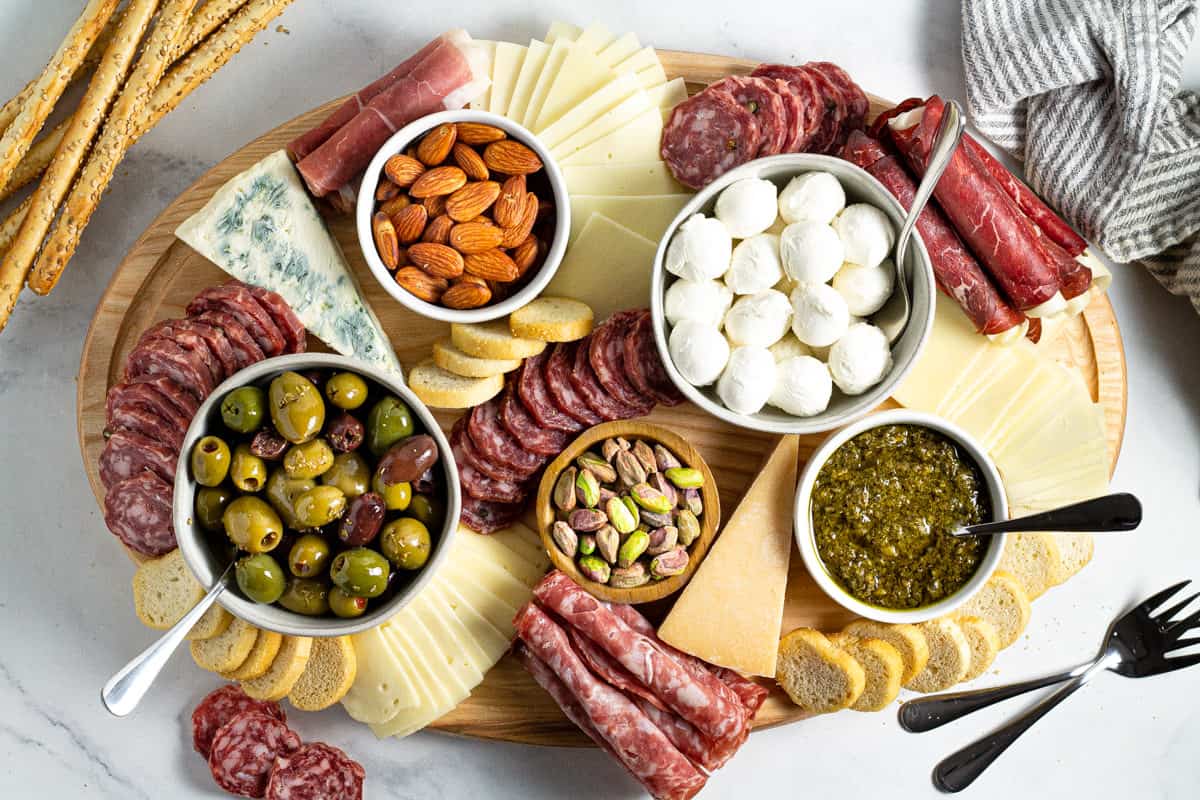 Overhead shot of a cutting board filled with meat and cheese creating a cheese board