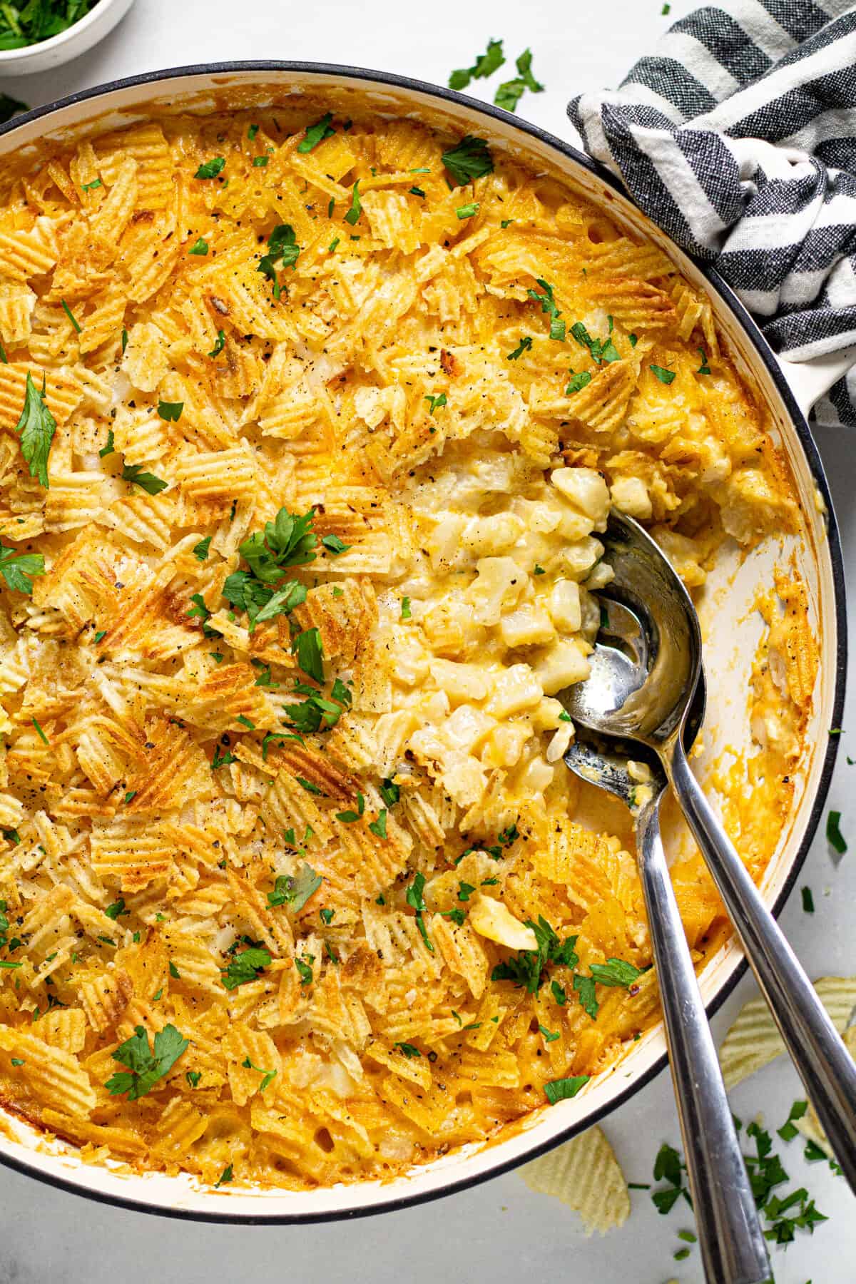 Overhead shot of a large pan filled with cheesy potato casserole garnished with fresh parsley 