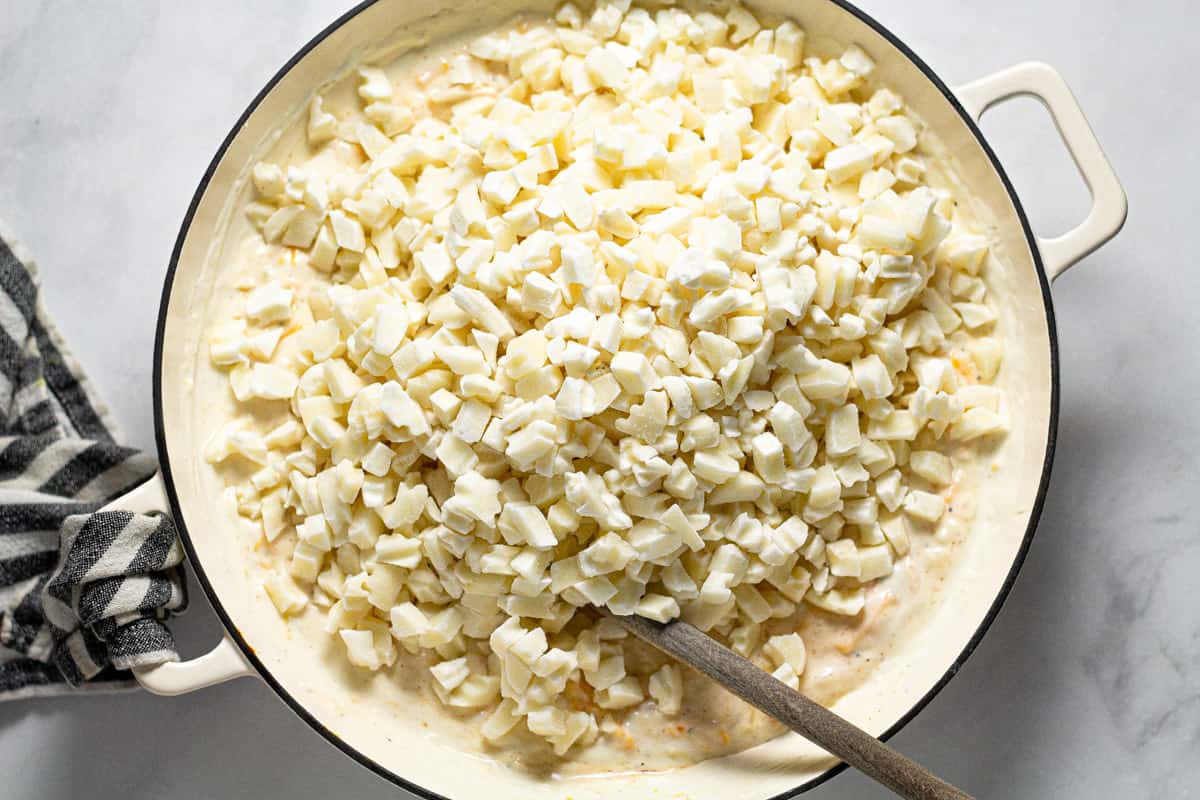 Large white pan filled with ingredients to make cheesy potatoes