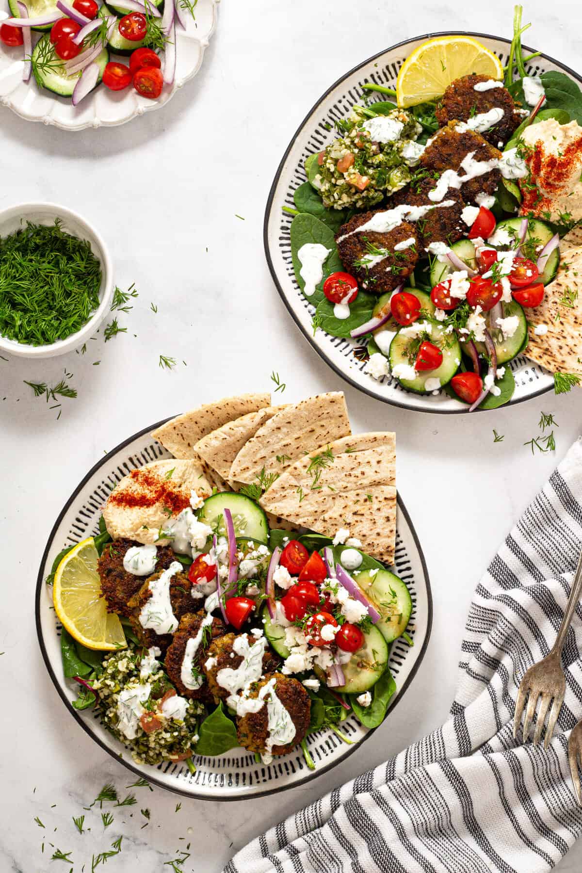 Two plates filled with falafel tzatziki and pita bread
