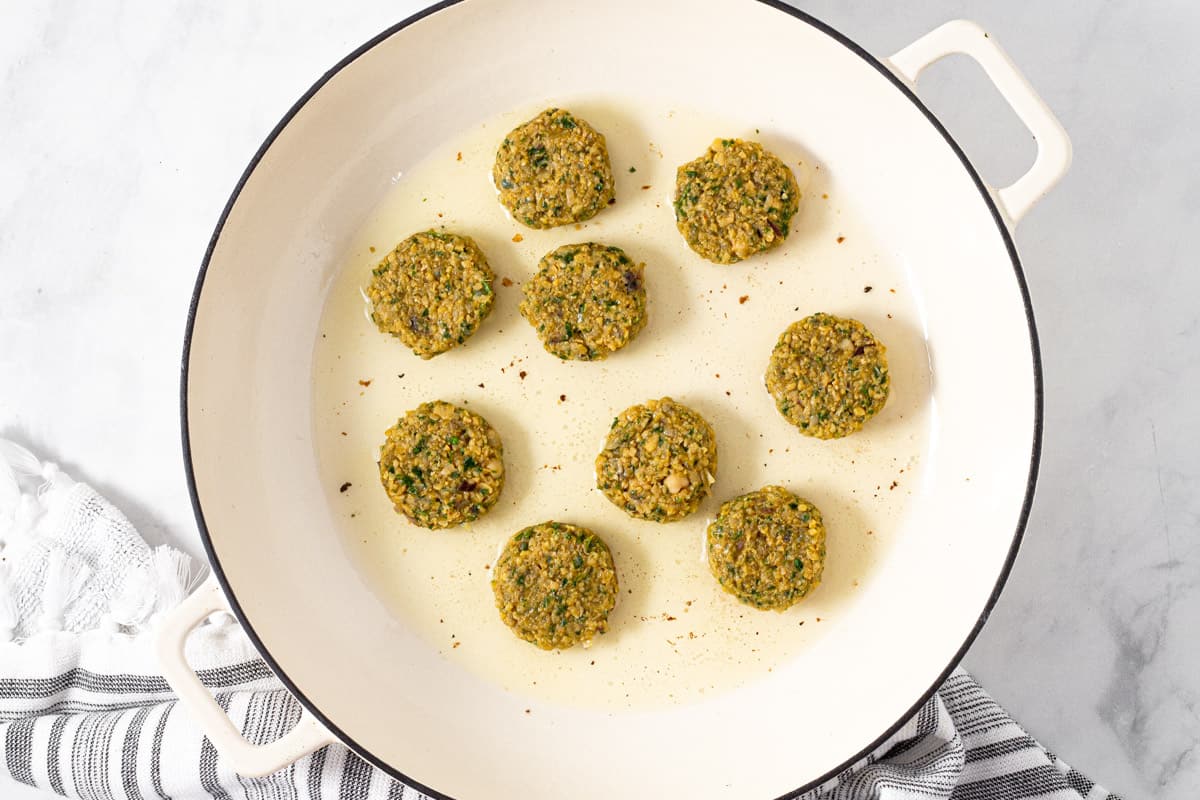 A large white pan filled with round discs of falafel