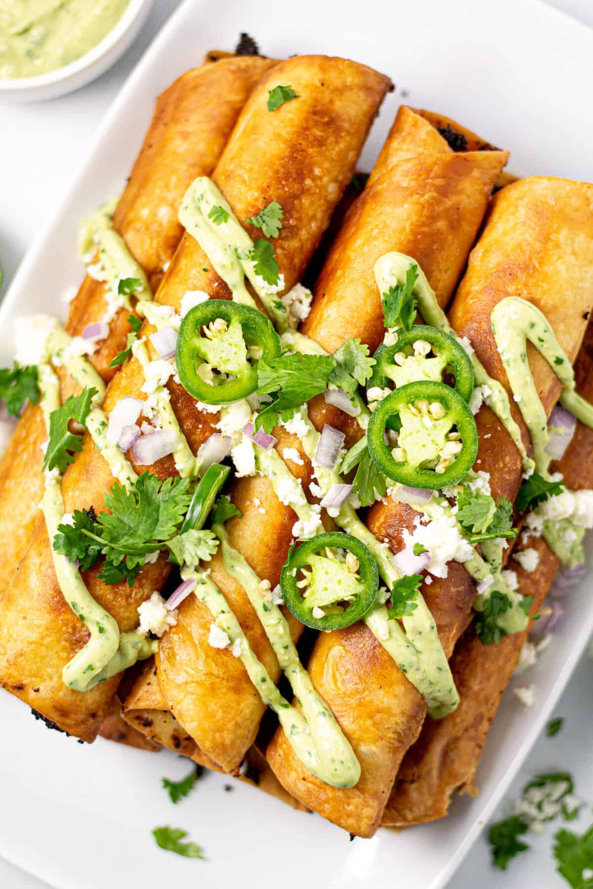 Overhead shot of a platter filled with flautas garnished with cilantro