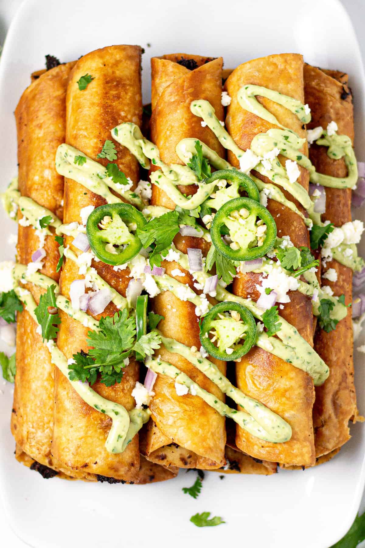 Overhead shot of a platter filled with flautas garnished with cilantro