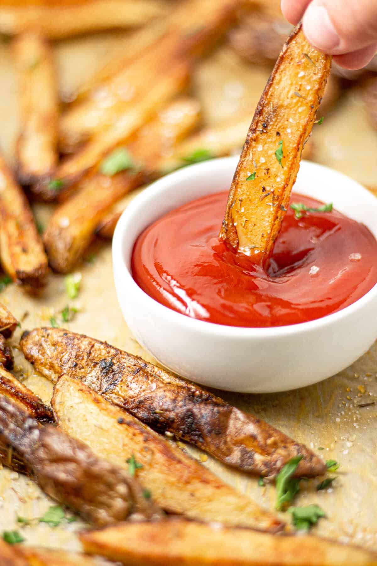 Close up shot of a French fry being dipped into a small dish of ketchup 
