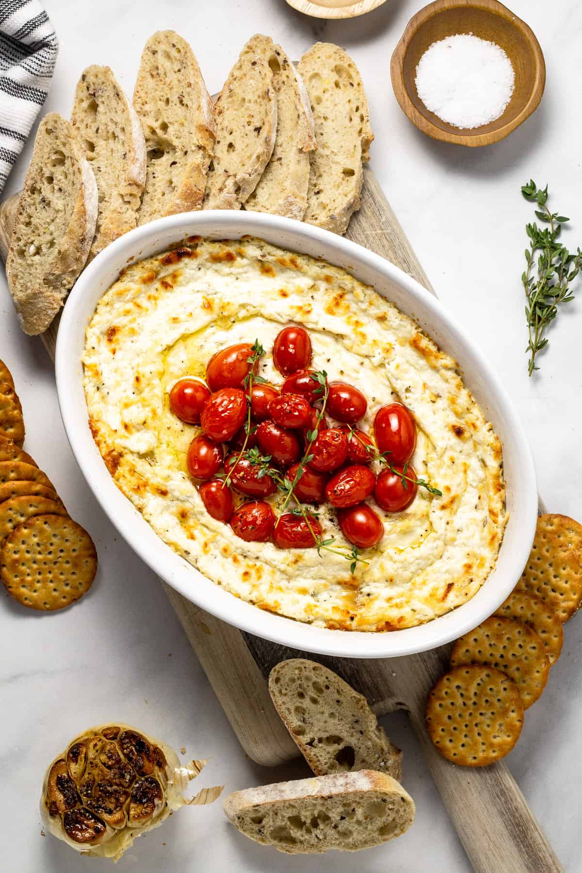 Overshot shot of baked goat cheese dip garnished with roasted tomatoes and fresh thyme.