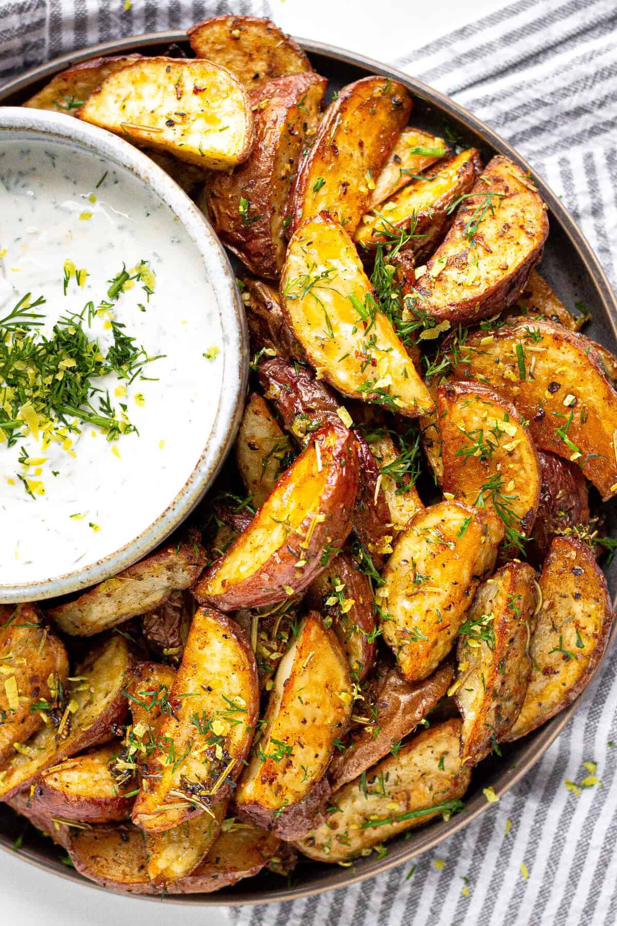 Overhead shot of plate filled with Greek Potato Wedges served with yogurt sauce