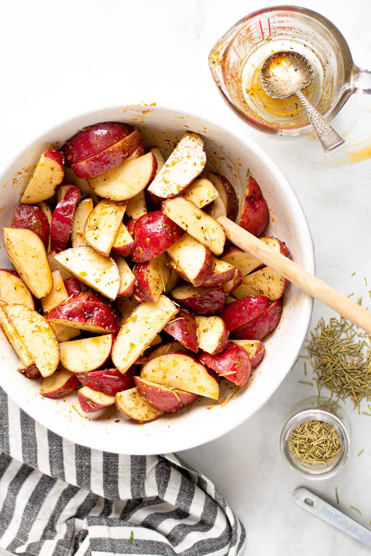 Overhead shot of a bowl of potato wedges tossed in olive oil and seasonings