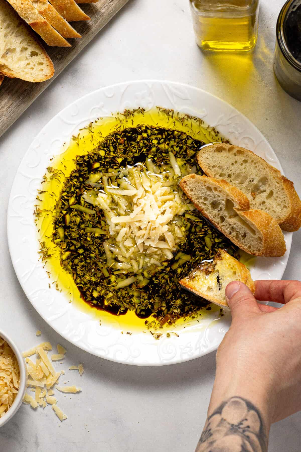 Overhead shot of a plate filled with olive oil and balsamic vinegar dip with Parmesan cheese and herbs