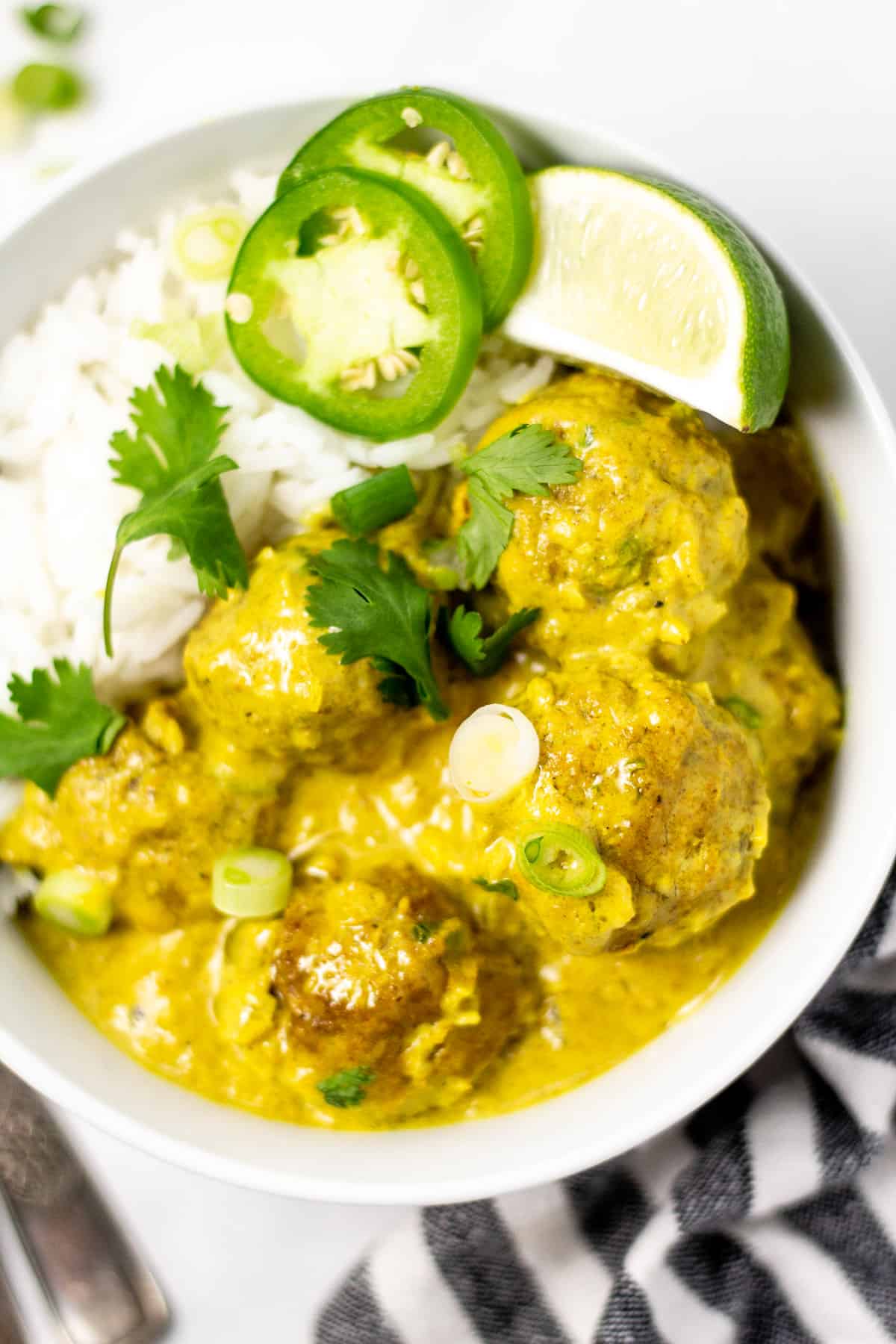 Close up shot of curried pork meatballs garnished with fresh cilantro on a bed of white rice