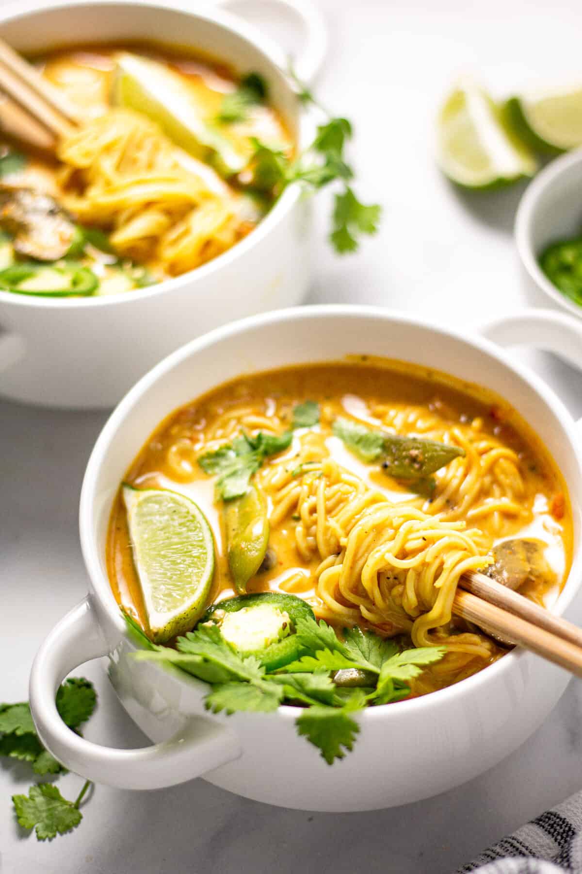 Two white bowls filled with vegan curry ramen garnished with fresh cilantro. 