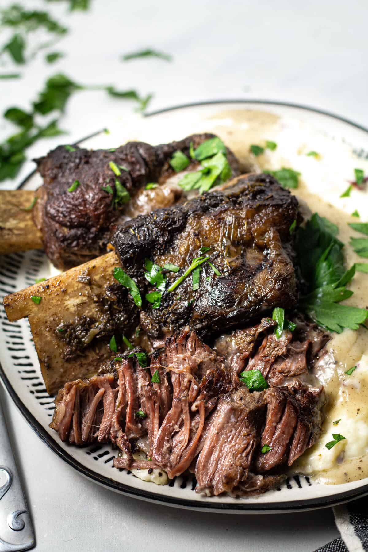 Overhead shot of a plate filled with short ribs and homemade mashed potatoes garnished with parsley 