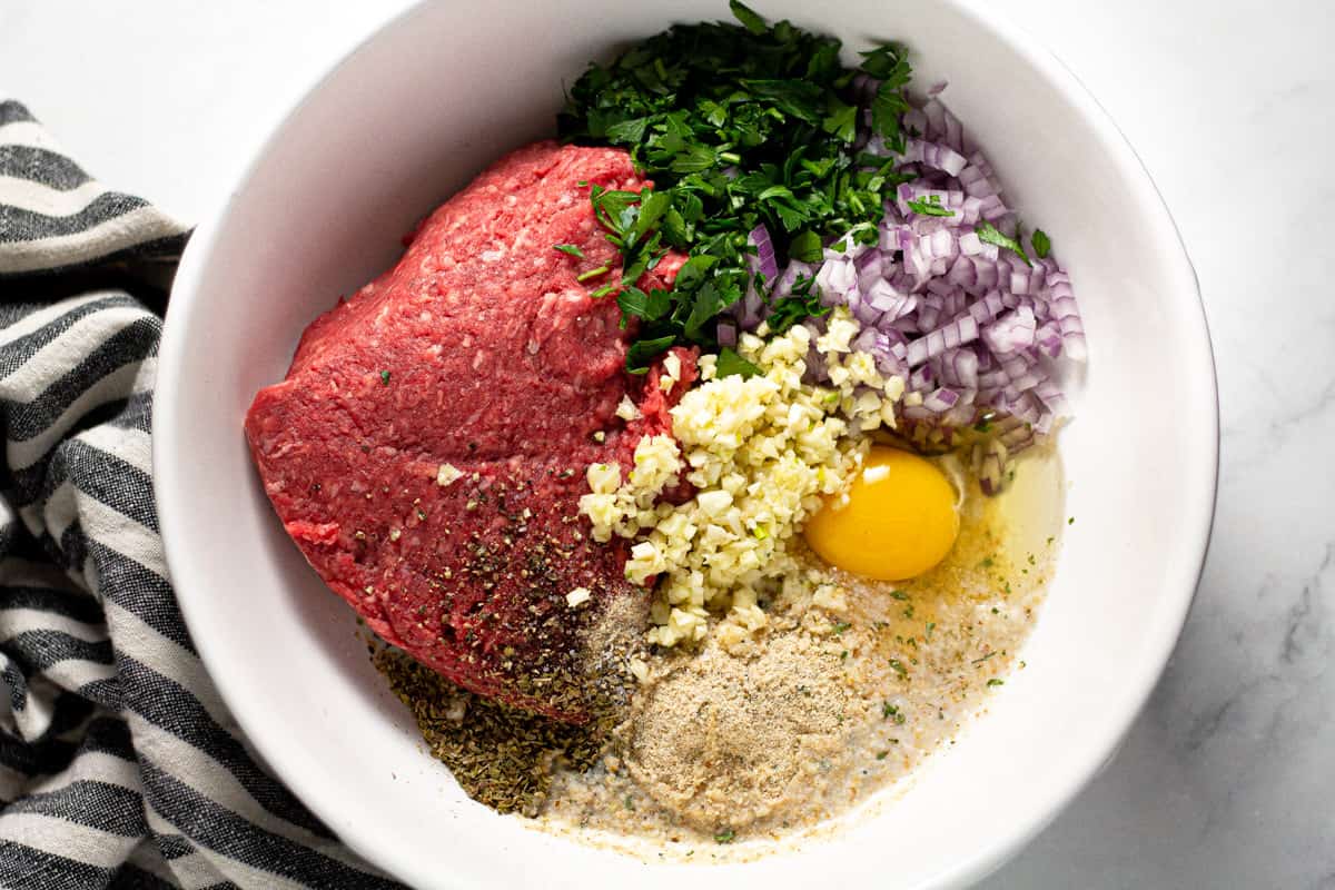 White bowl filled with ingredients to make beef meatballs