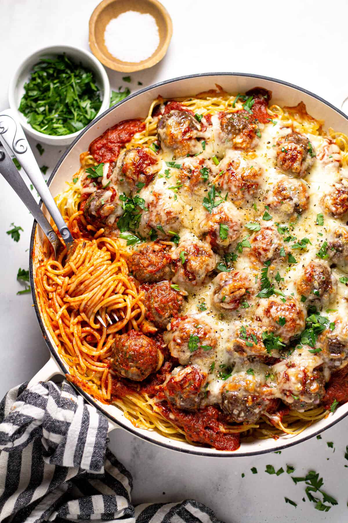 Overhead shot of a pan filled with baked spaghetti and meatballs garnished with fresh parsley