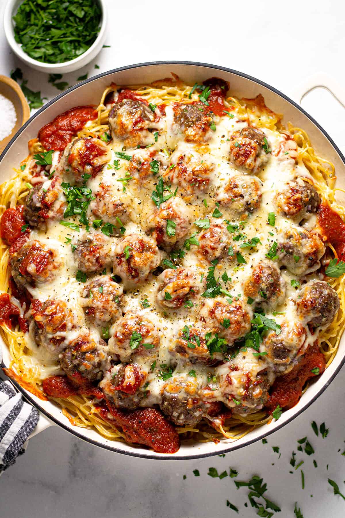 Overhead shot of a pan filled with baked spaghetti and meatballs garnished with fresh parsley
