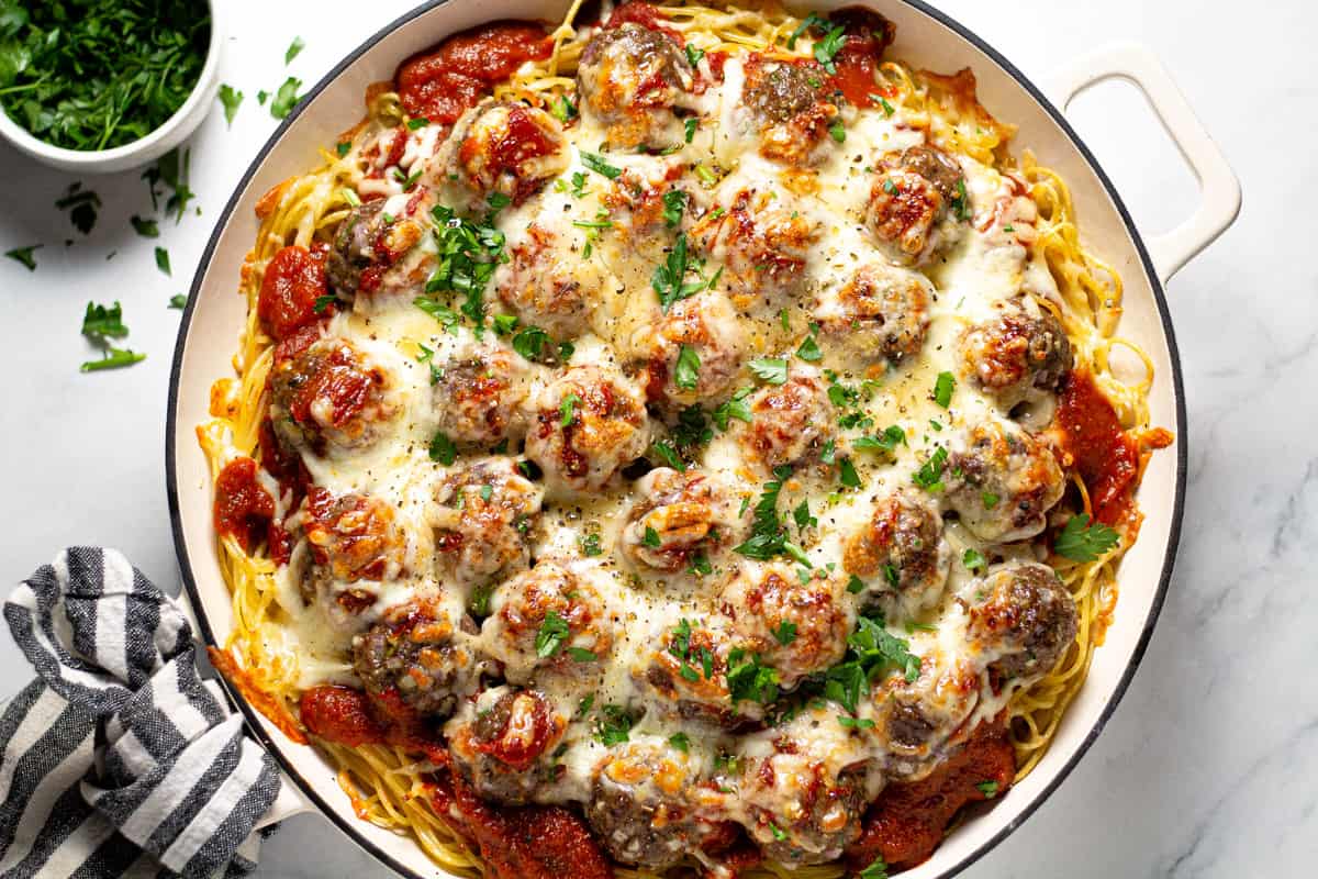 Overhead shot of a pan filled with baked spaghetti and meatballs garnished with fresh parsley
