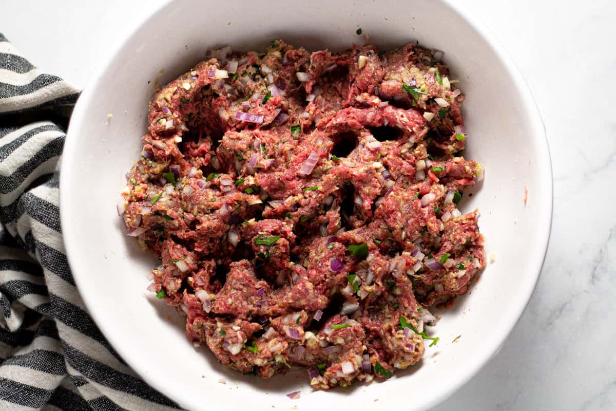 White bowl filled with ingredients to make beef meatballs