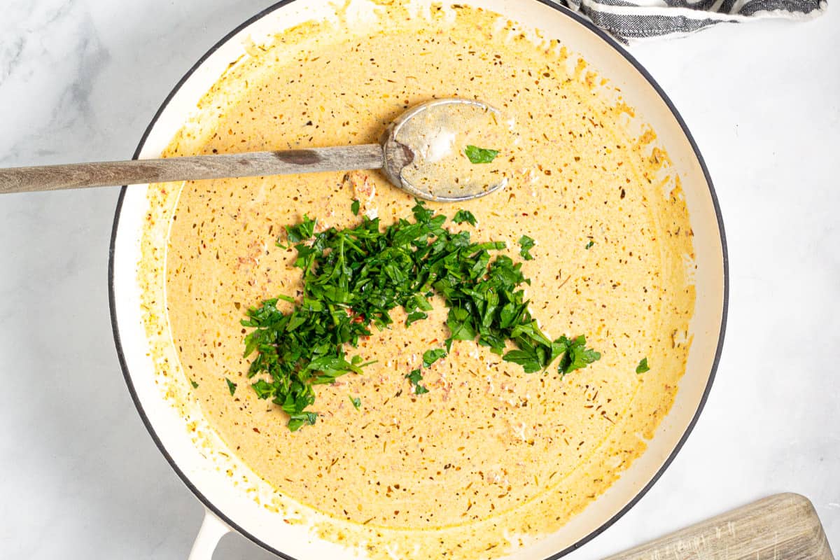 Parsley and sun dried tomato cream sauce in a large white pan 